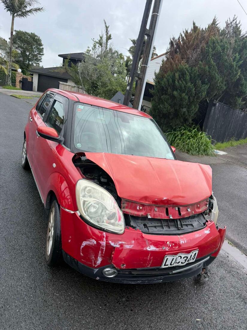Red hatchback with a smashed front end waiting for removal