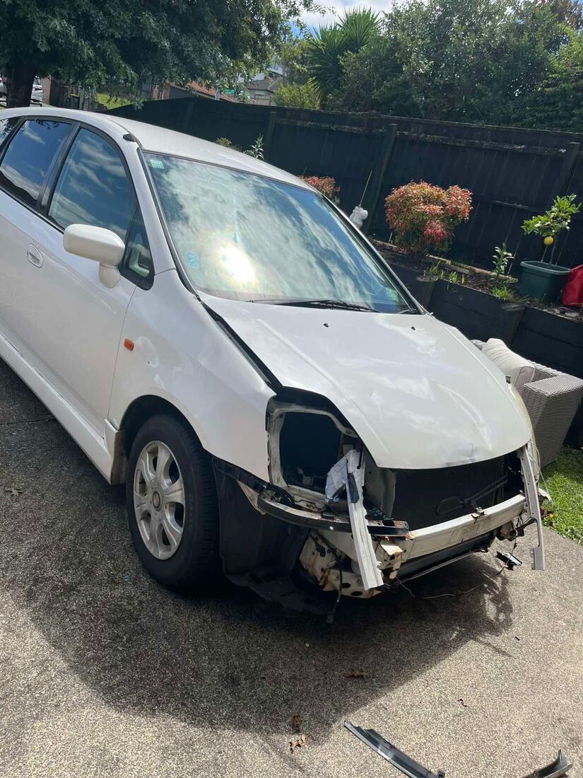 White people mover with front bumper and headlight torn off