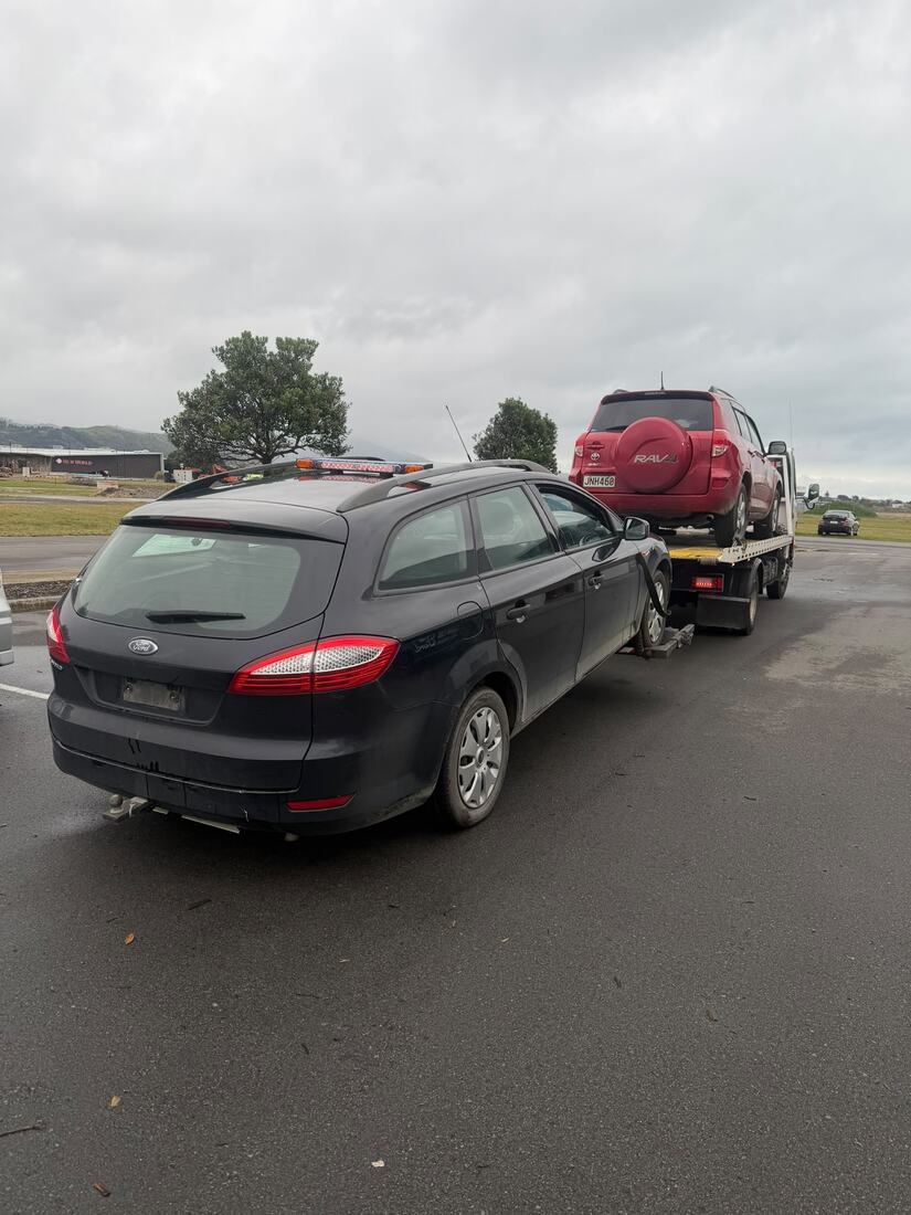 Black Ford wagon waiting beside the tow truck for removal