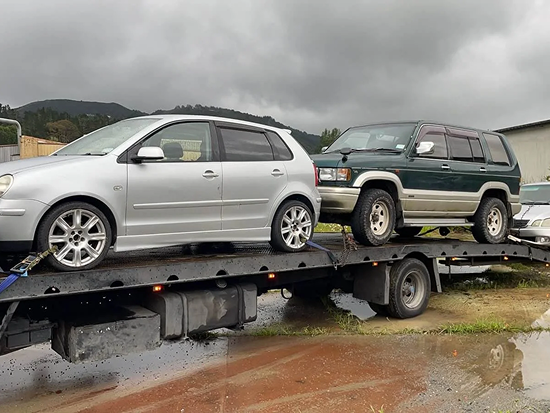 Tow truck transporting three scrap cars for removal in Whakatane